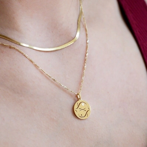 Layered gold 12 zodiac pendant necklace featuring flat snake chain and circular medallion