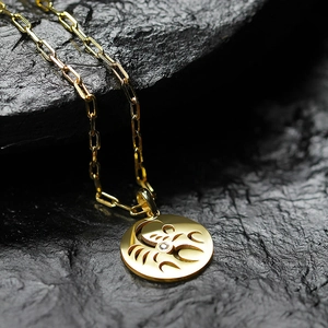 Golden paperclip chain necklace with a hollow zodiac Scorpio pendant on dark stone
