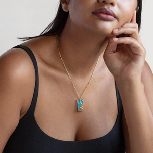 Dettaglio di una collana di tarocchi vintage con rilievo dorato su ciondolo rettangolare blu
