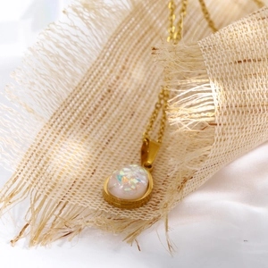 Nahaufnahme des Wassertropfen-Opal-Anhängers an einer goldenen Titanstahlkette auf Leinen