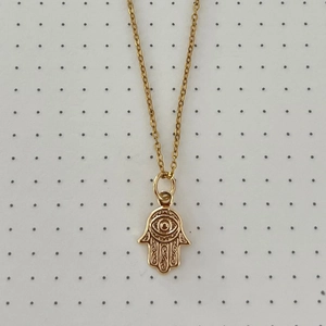 Detalle del collar con colgante mano de Fátima dorado con ojo central y grabados intrincados
