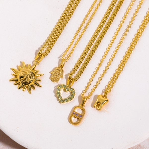 Collar dorado con colgantes de sol, mano de fátima, corazón y diente con circonitas