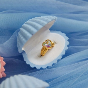 Macro shot of gold heart ring with iridescent opal stone in a blue shell jewelry box