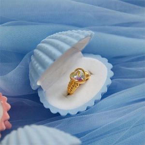 Detail of gold heart ring with rainbow opal in a blue shell box on soft blue tulle
