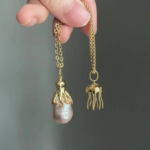 Detailed close-up of octopus and jellyfish gold pendants with baroque pearls and crystals