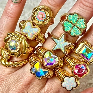 Gold-plated rings with colorful opal butterflies, stars, and hearts on model's hand