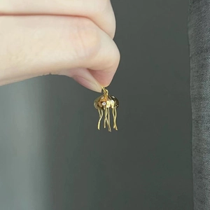 Detailed close-up of gold jellyfish pendant with sparkling zircons and delicate metal tassels
