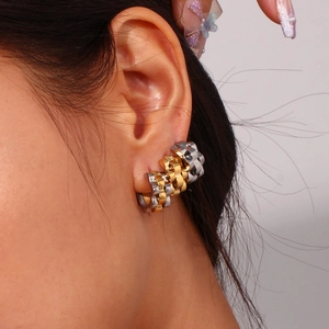 Detailed close-up of two-tone gold and silver chain link earrings worn on the ear