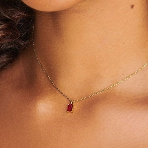 Close-up of a 18K gold plated titanium necklace with a red rectangular birthstone pendant