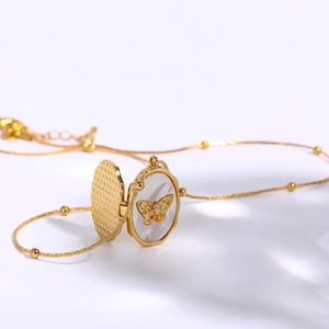 Gold oval locket necklace with butterfly motif and mother of pearl inlay on white base
