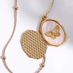 Gold oval locket necklace with mesh texture and butterfly shell interior detail