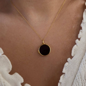 Elegante collana d'oro con ciondolo tondo in conchiglia nera indossata sulla clavicola