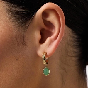 Gold textured hoop earrings featuring green aventurine stones on person wearing them