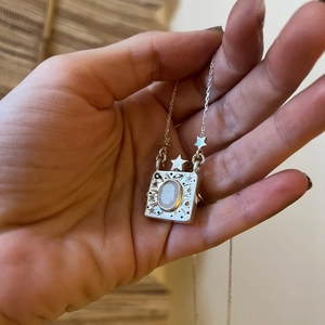 Vintage silver locket necklace with moonstone pendant featuring celestial star and moon patterns