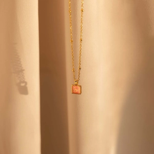 Dettaglio della collana in titanio dorato con ciondolo quadrato in opale rosa su seta