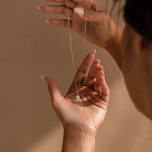 Dettaglio di una collana in acciaio al titanio dorato con pendente rettangolare in opale