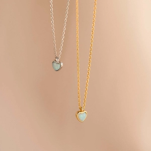 Dettaglio di collane in oro e argento con pendenti a cuore in opale su catene sottili