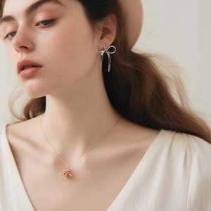 Dettaglio di orecchini a fiocco e collana floreale indossati da una modella donna