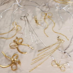 Dettaglio di orecchini a fiocco in titanio con placcatura in oro e perle eleganti
