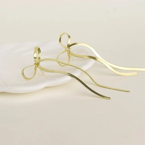 Primo piano dei dettagli di orecchini a fiocco dorati con lunghe nappe a catena snake