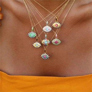 Nahaufnahme von goldenen Evil Eye-Halsketten mit Emaille und Kristalldetails an einem Model