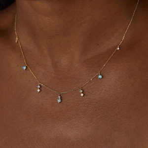 Detail of a double-layered gold-plated titanium necklace with opal and zircon pendants