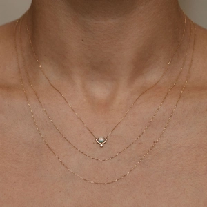 Close-up of triple-layered gold necklace with round opal pendant and delicate O-chains