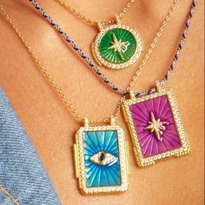 Gros plan de colliers de cartes de tarot avec pendentifs en émail et chaînes dorées
