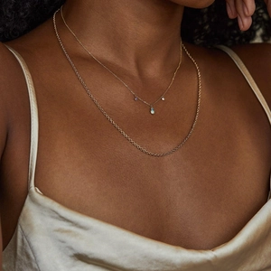 Close-up of double layer gold plated opal teardrop necklace worn on model neck