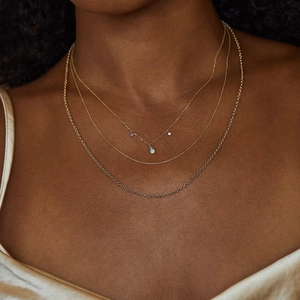 Detail of layered gold necklaces featuring a central opal pendant and sparkling accents