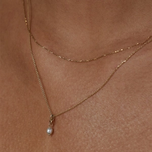 Close-up of double-layer gold necklace featuring a delicate white round pearl pendant
