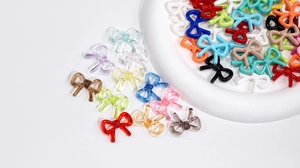 Close-up of colorful bow-shaped acrylic beads with detailed woven texture for DIY crafts