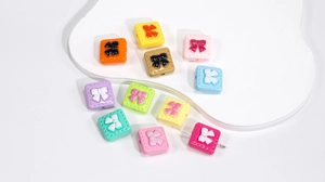 Macro view of macaron acrylic square beads with bow relief and central threading holes