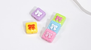 Detailed view of colorful acrylic square beads with 3D bow design for DIY jewelry making