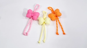 Detailed macro view of colorful bow phone charms in pink, yellow and orange woven fabric