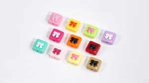 Macro shot of colorful acrylic square beads with bow relief for DIY jewelry making