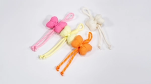 Detail of colorful bow-knot phone charms in pink, yellow, orange and cream fabrics