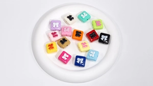 Macro shot of colorful acrylic square bow beads with stitch textures and side holes