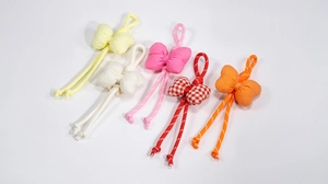 Detail view of five colorful handmade bow pendants in checkered and solid woven styles