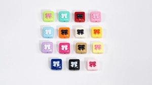 Macro detail of acrylic square beads with 3D bow relief for DIY jewelry crafts