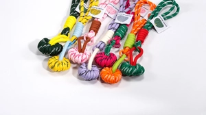 Detailed macro of colorful paracord phone straps with woven pumpkin knots and fashion labels