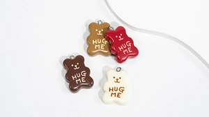 Detail of colorful resin bear pendants with Hug Me text and metal loops for DIY crafts