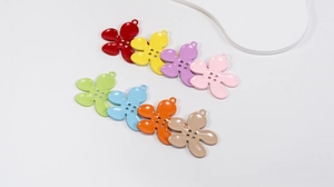 Macro detail of multi-colored five-petal flower alloy pendants with four-hole centers