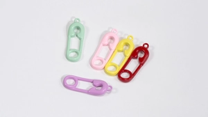 Dettaglio di cinque ciondoli a spilla da balia colorati in menta, rosa, giallo, rosso e viola