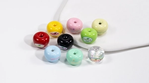 Macro detail of apple-shaped acrylic beads with 100% APPLE print for DIY jewelry making