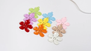 Flat lay of colorful five-petal alloy flower charms with button center for DIY accessories