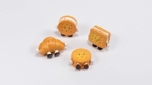 Close-up of four cute acrylic cartoon biscuit and croissant charms with smiley faces