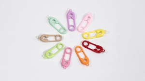 Dettaglio di ciondoli colorati a forma di spilla da balia in lega per gioielli DIY e portachiavi