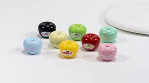 Macro detail of apple-shaped acrylic beads in assorted colors with glossy finish and top holes