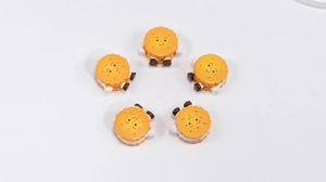 Close-up of five cute acrylic biscuit charms with smiling faces for DIY crafts